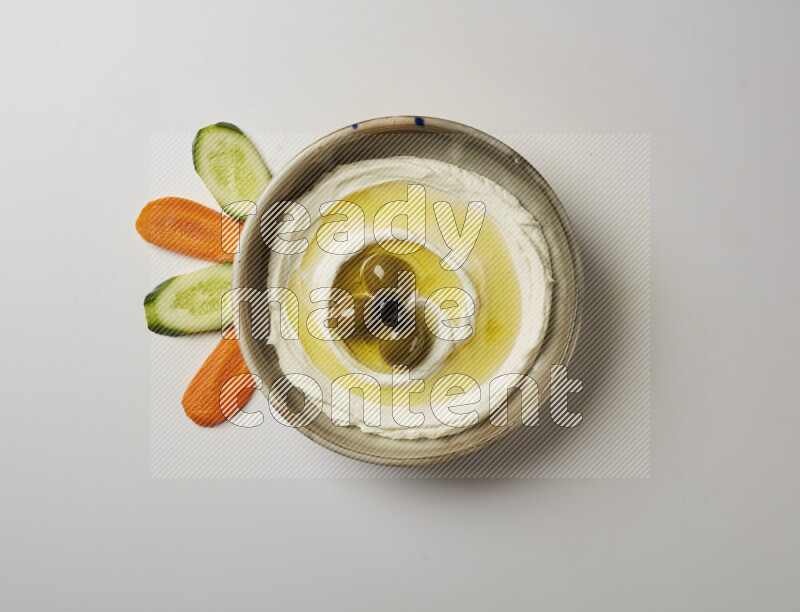 Lebnah garnished with whole olives in a grey pottery plate on a white background