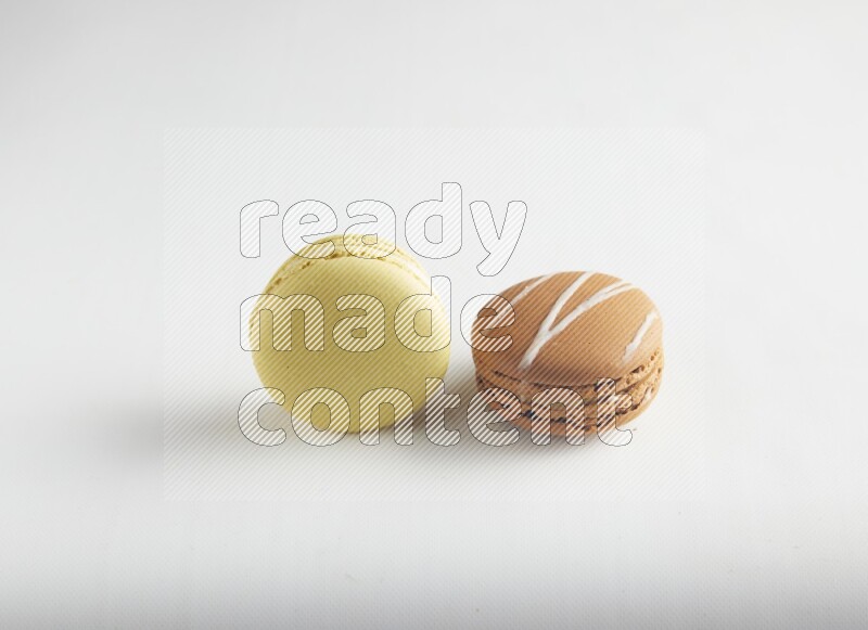 45º Shot of of two assorted Brown Irish Cream, and Yellow Lime macarons on white background