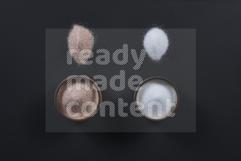 2 pottery bowls one is filled with himalayan salt and the other with white salt on black background