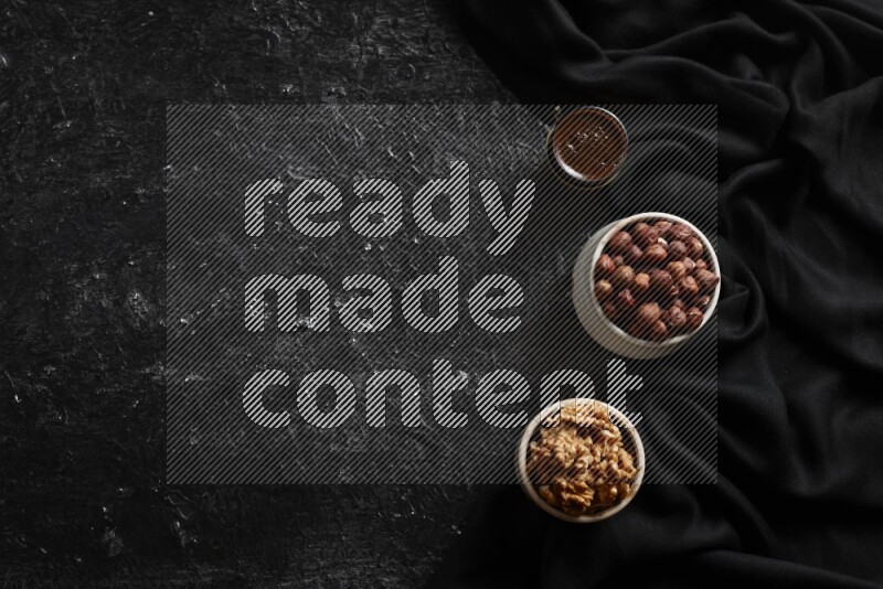 مكسرات في أطباق فخارية مع القهوة علي خلفية سوداء خشبية