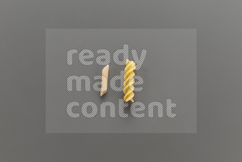 Mini penne pasta with other types of pasta on grey background