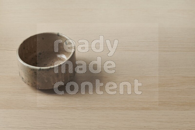 A multicolored pottery bowl on light wooden background