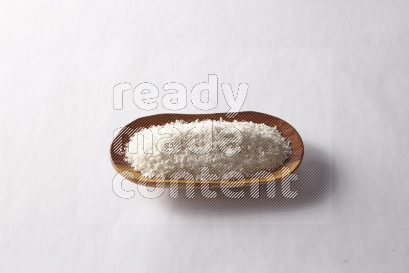 Desiccated coconuts in a wooden plate on white background