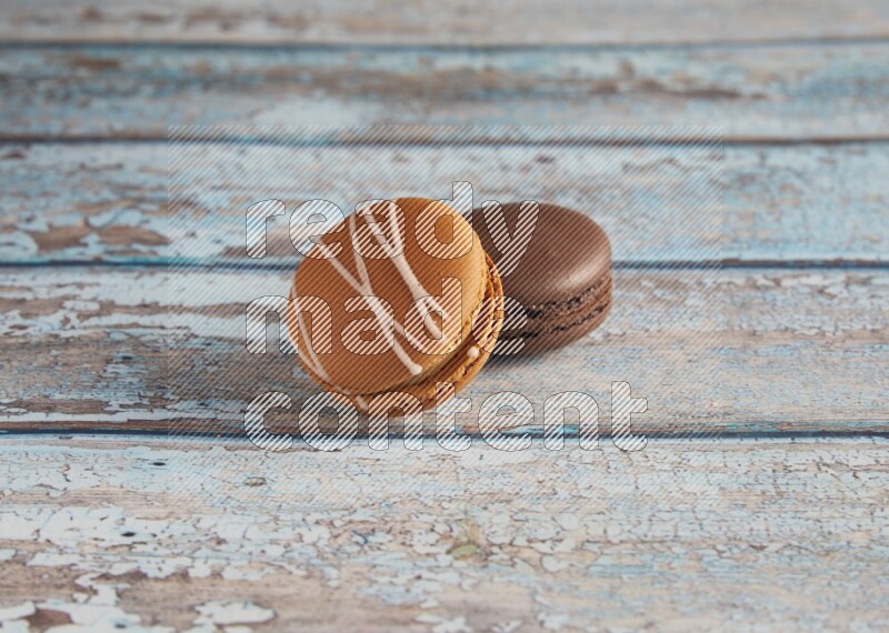 45º Shot of of two assorted Brown Irish Cream, and Brown Dark Chocolate macarons on light blue background
