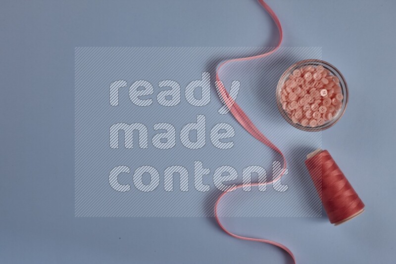 مجموعة من أدوات الخياطة والتفصيل زهرية اللون على خلفية زرقاء