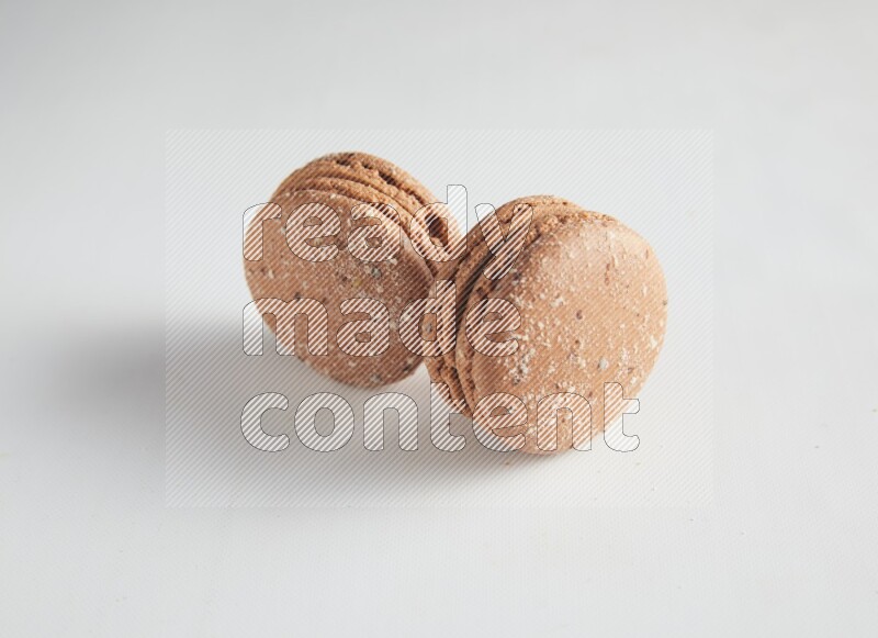 45º Shot of two Brown Hazelnuts macarons on white background