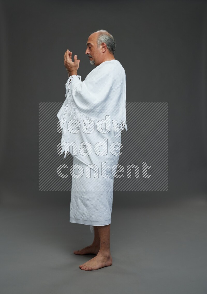 A man wearing Ehram Standing dua'a on gray background
