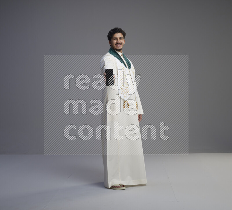 رجل سعودي يرتدي ثوب ابيض و شال يحمل جوال