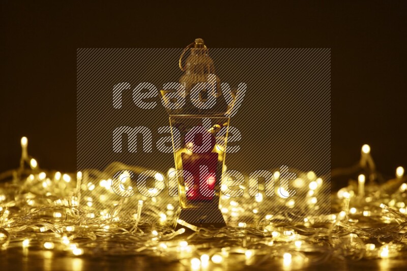 A traditional ramadan lantern surrounded by glowing fairy lights in a dark setup