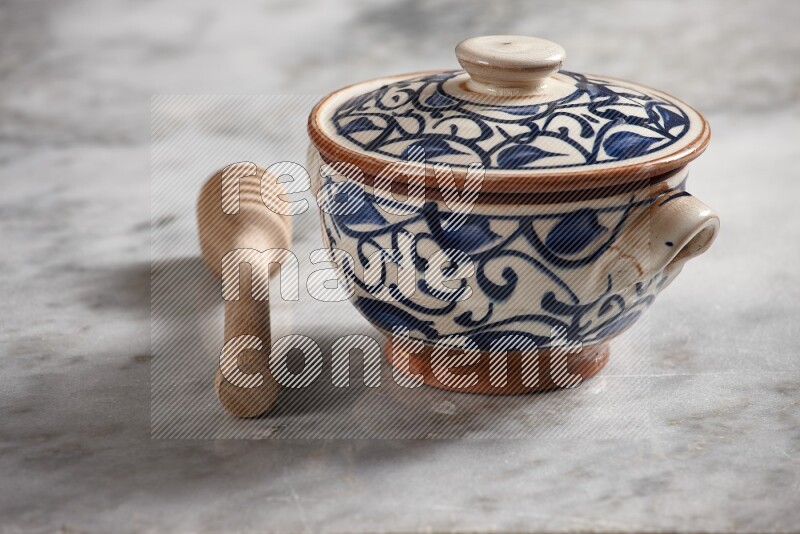 Decorative pottery pot with wooden honey dipper on the side on grey marble background