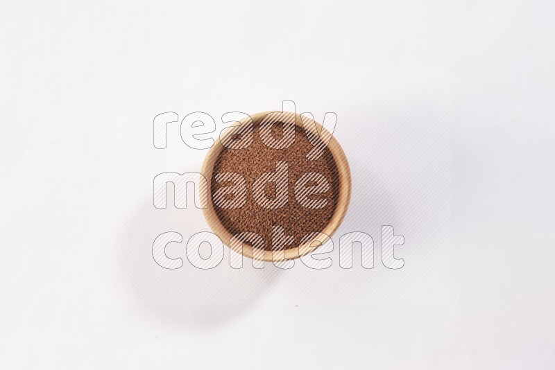 A wooden bowl full of garden cress seeds on a white flooring