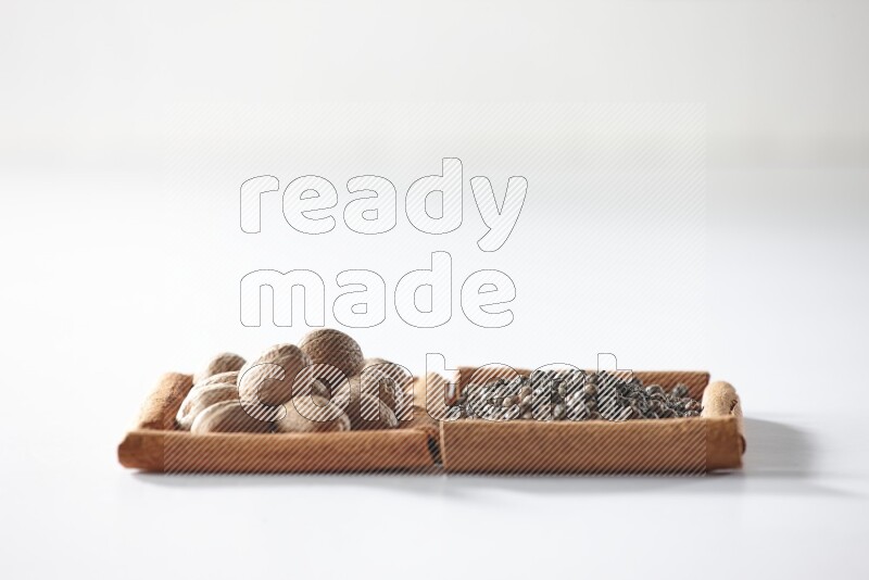 2 squares of cinnamon sticks full of black pepper and nutmegs on white flooring