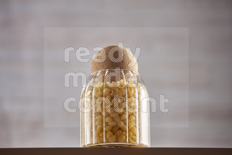 Raw pasta in glass jars on beige background