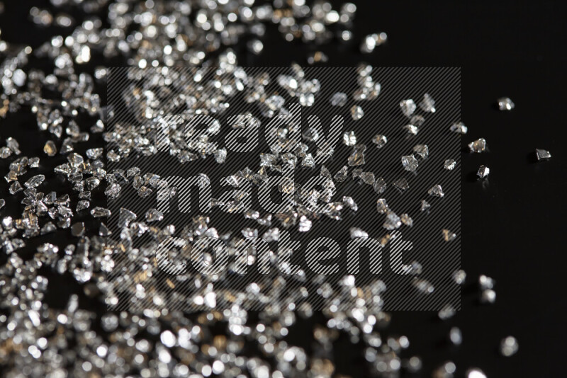 Silver shimmering fragments of glass scattered on a black background