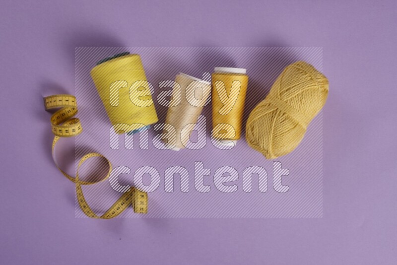 A yellow and purple collection of sewing and tailoring tools arranged on a purple background