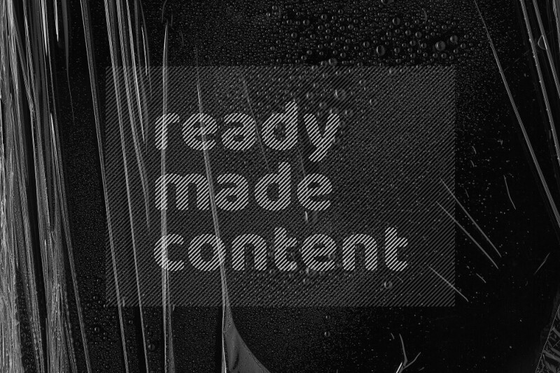 تظهر الصورة غلاف من البلاستيك مع بعض قطرات الماء فوقه علي خلفية داكنة