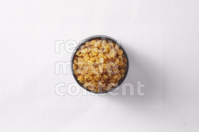 Raisins in a black pottery bowl on white background