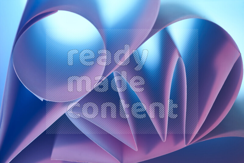 An artistic display of paper folds creating a harmonious blend of geometric shapes, highlighted by soft lighting in blue and pink tones