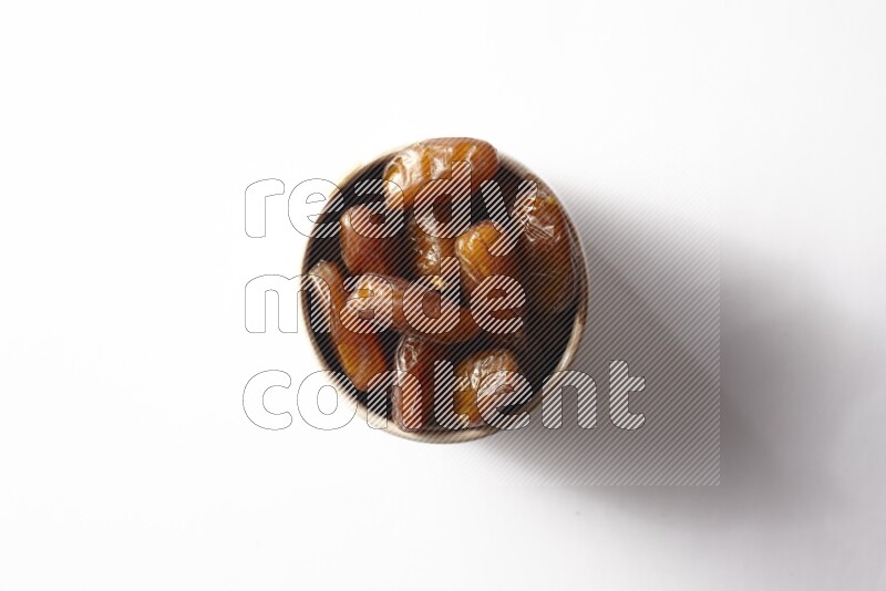 Dates in a beige pottery bowl on white background