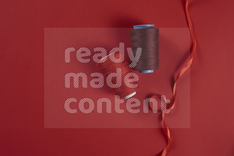 A red collection of sewing and tailoring tools arranged on a red background