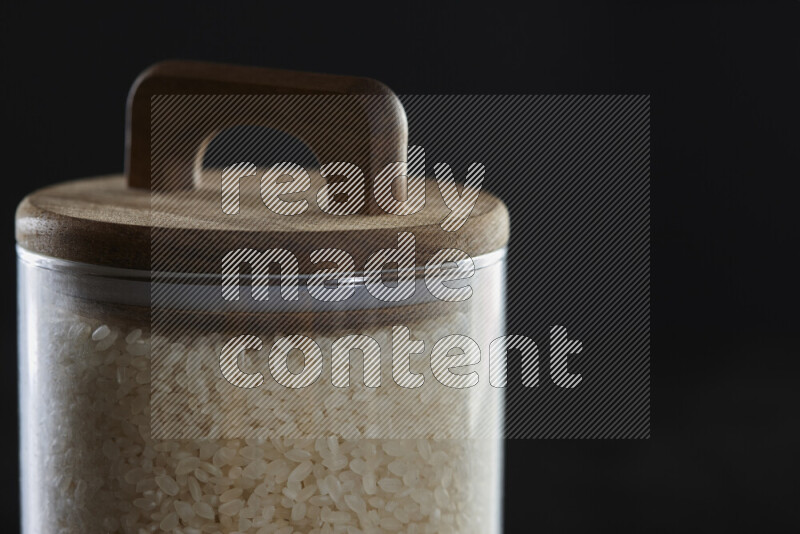 White rice in a glass jar on black background