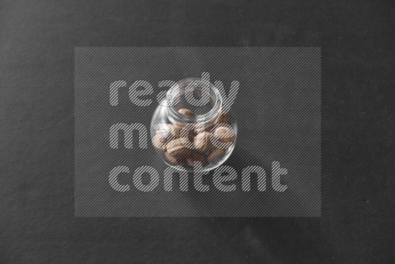 A glass spice jar full of nutmeg on black flooring