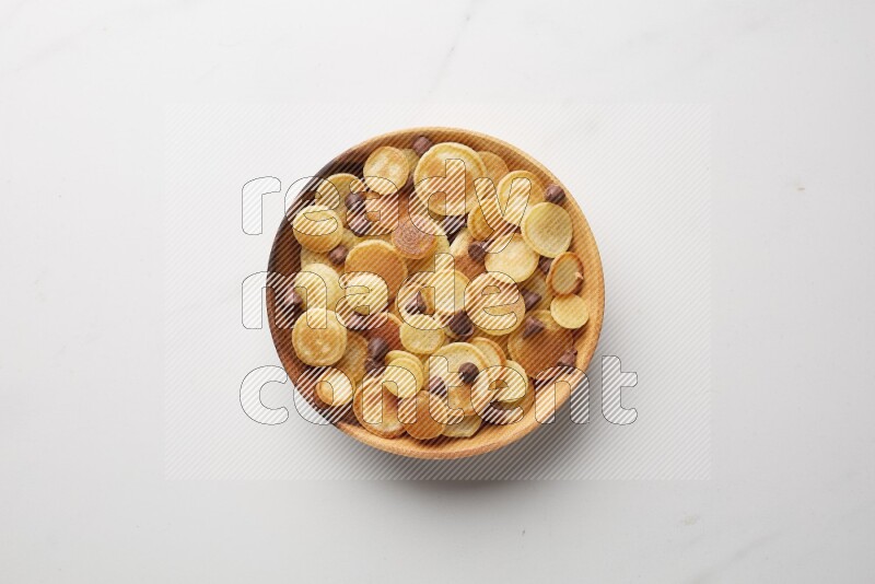 Top-view shot of chocolate chips cereal pancakes in a round bowl on white background