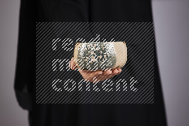 A woman in black abaya holding different pottery essentials in different positions
