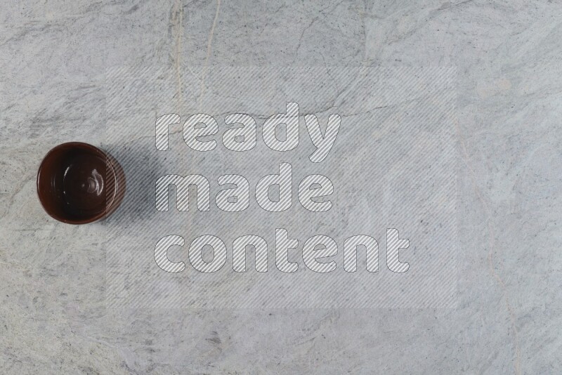 A brown pottery bowl on grey marble background