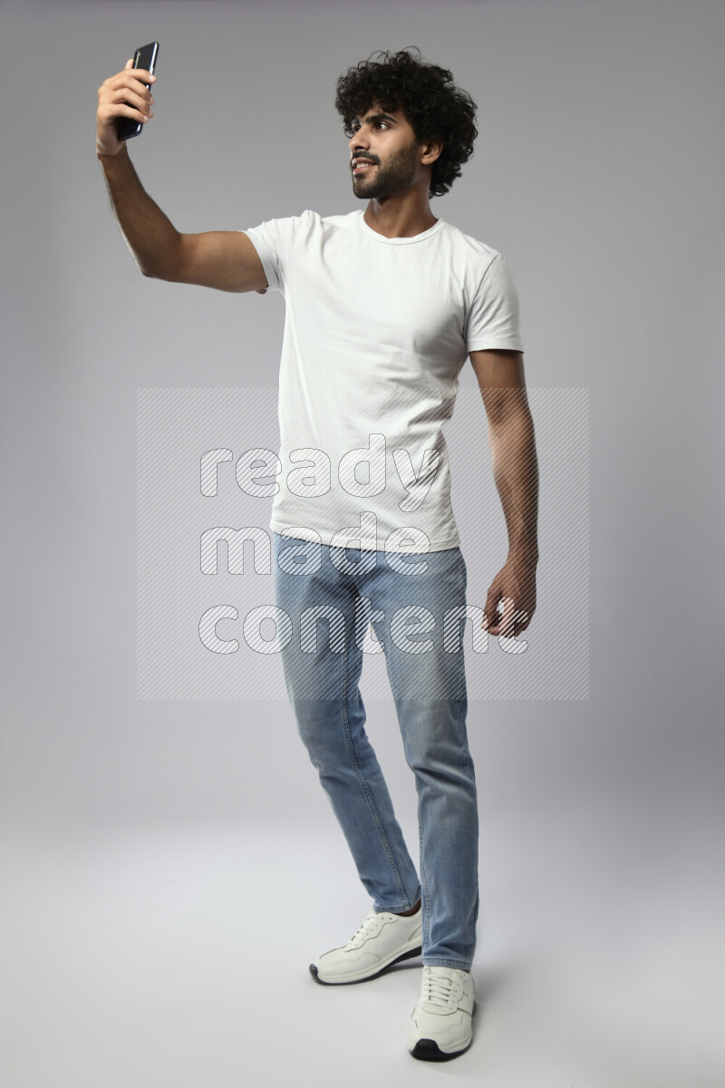 A man wearing casual standing and taking a selfie on white background