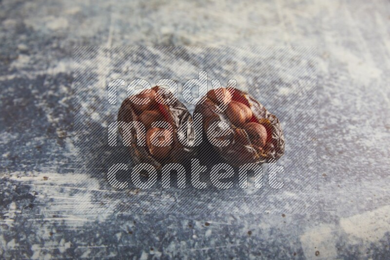 two hazelnuts stuffed madjoul dates on a rustic blue background