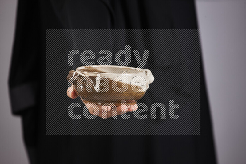 A woman in black abaya holding different pottery essentials in different positions