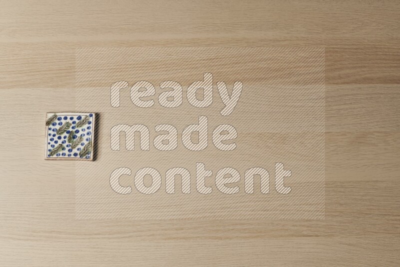 A decorative pottery coaster on light wooden background