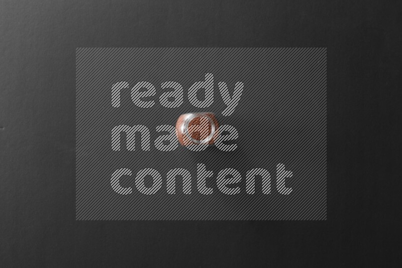 A glass spice jar full of garden cress on black flooring