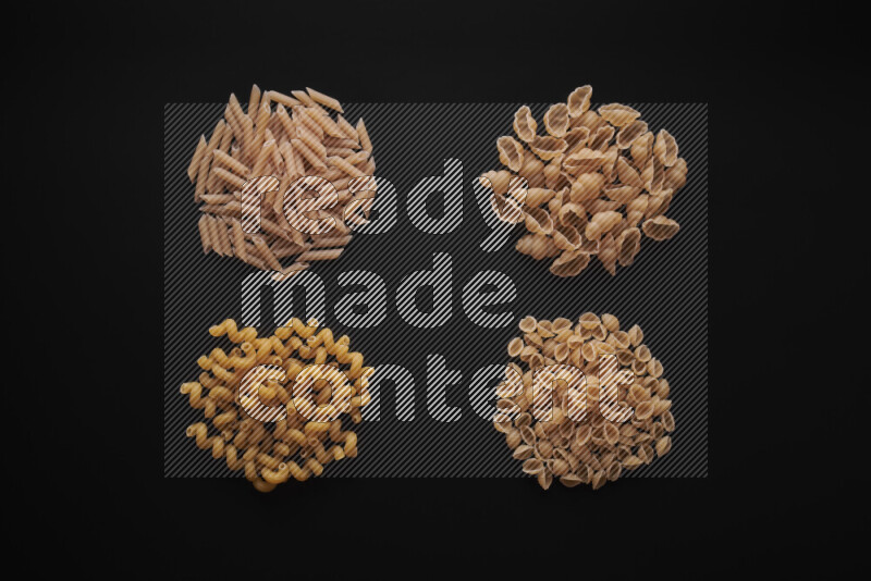 Different pasta types in bunches on black background