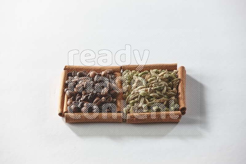 2 squares of cinnamon sticks full of cardamom and coffee beans on white flooring