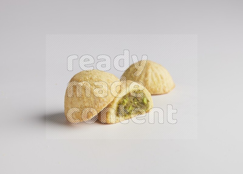 Three Pieces of Maamoul filled with pistachio paste  one of them is cut direct on white background