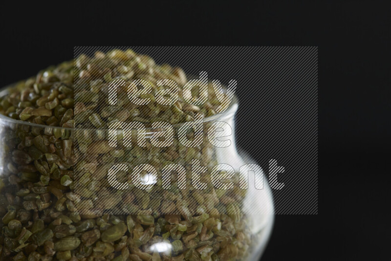 Freekeh in a glass jar on black background