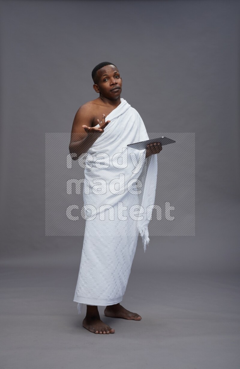 A man wearing Ehram Standing working on tablet on gray background