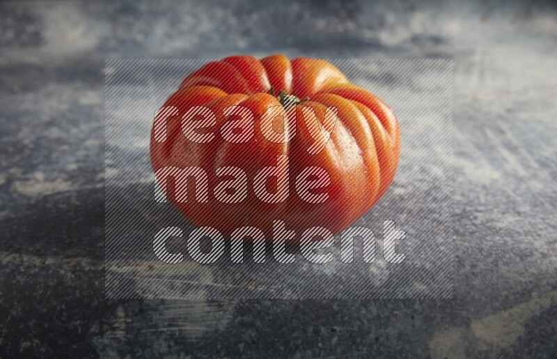 45 degree single heirloom tomato on a textured rustic blue background