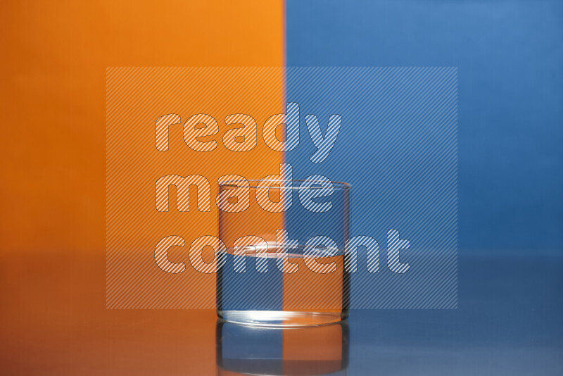 The image features a clear glassware filled with water, set against orange and blue background