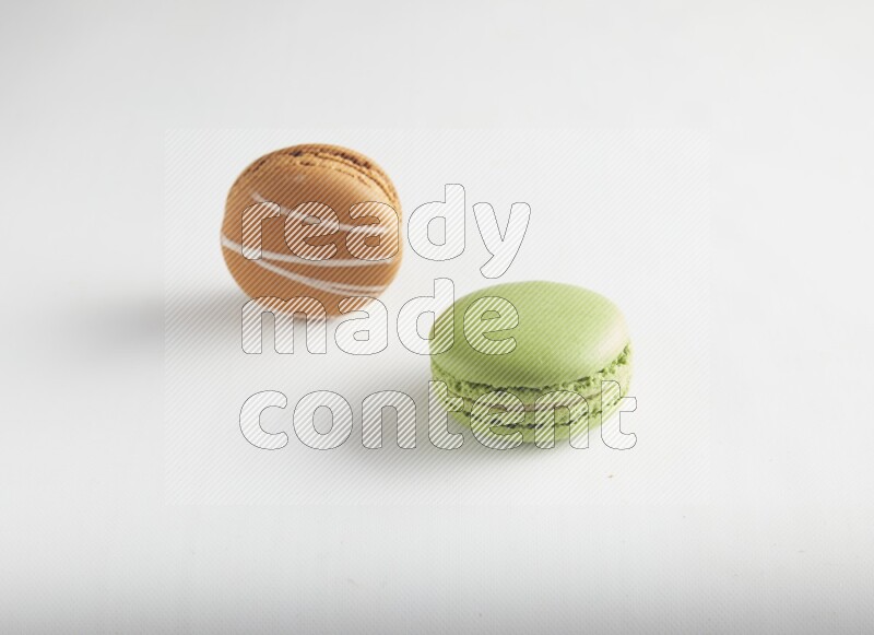 45º Shot of of two assorted Brown Irish Cream, and Green Pistachio macarons on white background