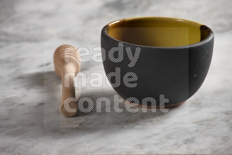 Multicolored pottery bowl with wooden honey dipper on the side on grey marble background