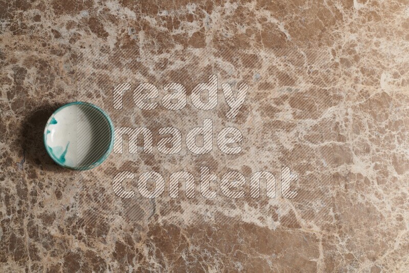 A multicolored pottery bowl on beige marble background