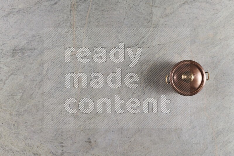 A small copper pot on grey marble background