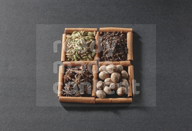 4 squares of cinnamon sticks full of cardamom, star anise, nutmegs and cloves on black flooring