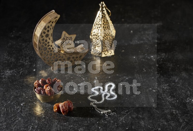 Dates in a metal bowl with prayer beads beside golden lanterns in a dark setup