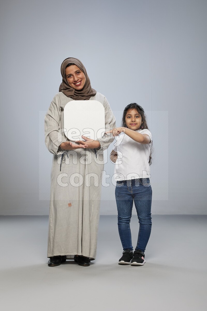Mom and daughter standing holding social media sign on gray background