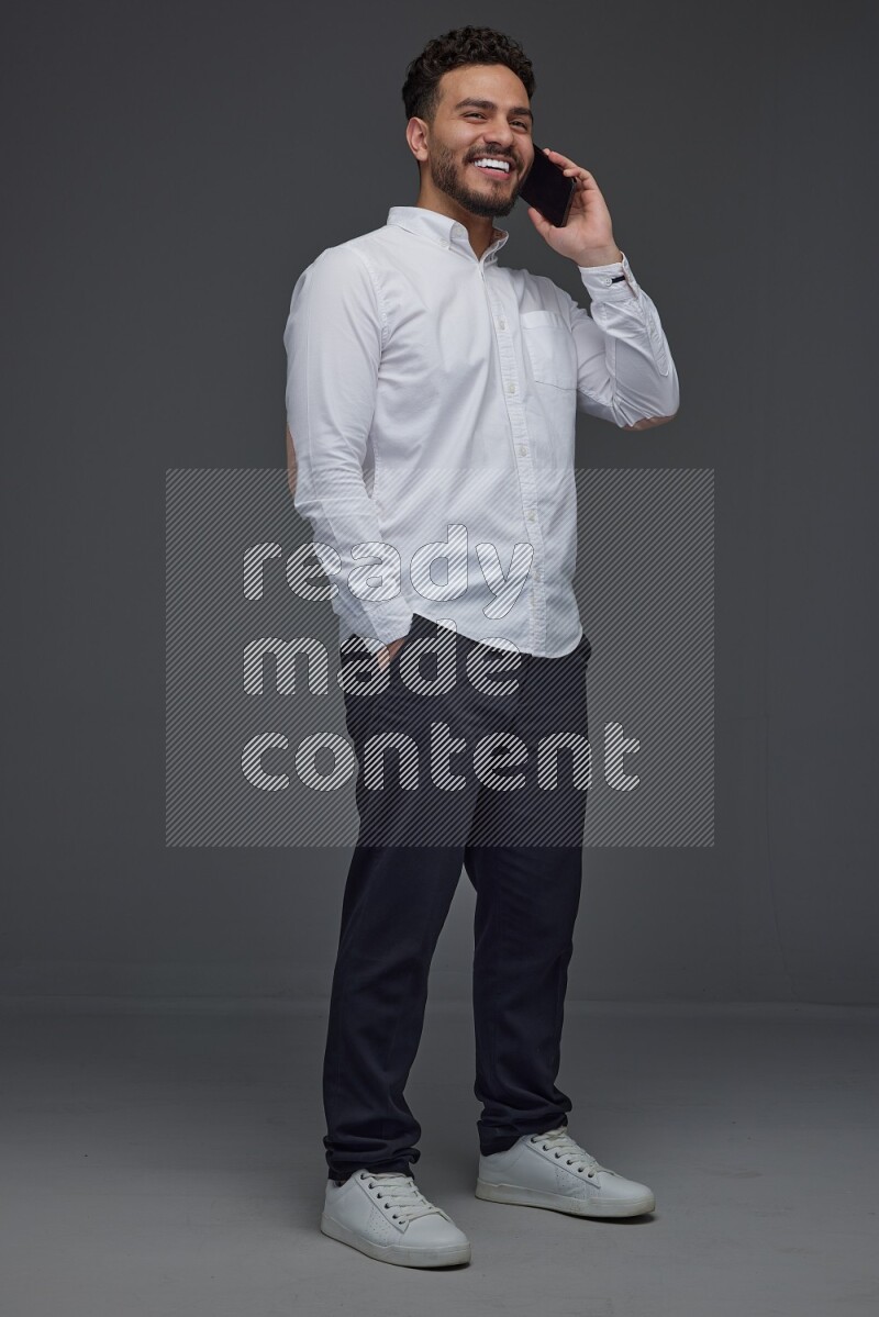 A man wearing smart casual talking in the phone eye level on a gray background