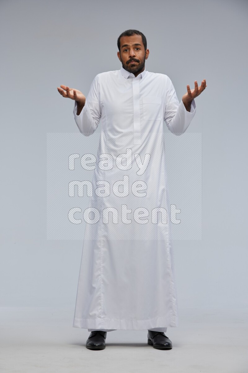 Saudi man Wearing Thob standing interacting with the camera on Gray background
